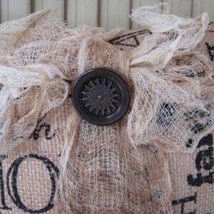 May include: A burlap pillow with a white lace bow and a brown button in the center. The pillow has the words "Home" and "Faith" printed on it.