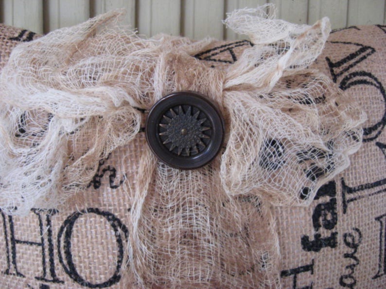 May include: A burlap pillow with a white lace bow and a brown button in the center. The pillow has the words "Home" and "Faith" printed on it.