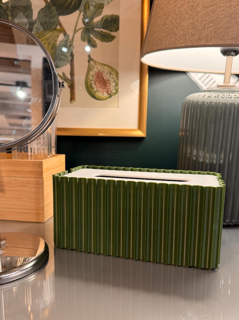 May include: A rectangular tissue box cover featuring a deep olive green exterior with a vertical ribbed texture and a contrasting smooth white top panel with a central rectangular opening for dispensing tissues.