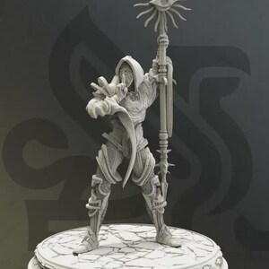 Può includere: Statuetta grigia dettagliata di una figura in abito che tiene in mano un bastone sormontato da un disegno a occhio. La figura è in piedi su una piattaforma circolare con un motivo di pietra crepata. Il bastone ha una serie di punte.