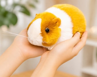Peut inclure: Une peluche en forme de cochon d'Inde avec une fourrure douce et duveteuse dans des tons jaune doré et blanc. Ce jouet en peluche présente des yeux sombres réalistes, un petit nez et de longues moustaches blanches fines sur le museau.