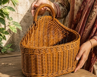 Peut inclure: Un panier tressé brun moyen de forme semi-circulaire avec une seule anse arquée sur le dessus. Le panier présente une conception structurée à dessus ouvert avec un motif de tissage vertical et horizontal cohérent sur tout le corps.