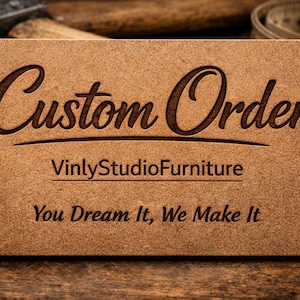 May include: A rectangular light brown wooden sign with dark brown laser-engraved text. The sign features the words Custom Order in a large script font, followed by VinlyStudioFurniture and the phrase You Dream It, We Make It in a standard font.