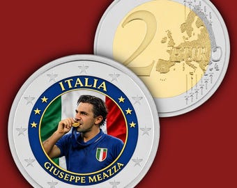 May include: A commemorative two-euro coin featuring a portrait of Giuseppe Meazza in a blue jersey biting a gold medal, set against the Italian flag. The coin is bordered by stars and the text ITALIA and GIUSEPPE MEAZZA, with the standard euro design.