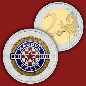 Può includere: Una moneta da due euro con un design commemorativo per l'Hajduk Spalato. Il dritto mostra un emblema a scacchi blu e bianco con una stella rossa, la scritta HAJDUK SPLIT e gli anni 1911 e 1961. Il rovescio mostra la mappa europea standard.