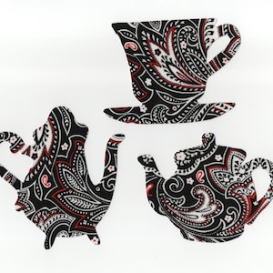 May include: Three paisley-patterned tea party cutouts in black, white, and red. The set includes a teacup and saucer, a teapot, and a tea kettle. The designs feature a detailed floral and swirl pattern.