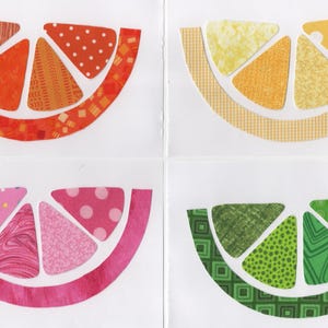 May include: Four colorful paper cutouts of citrus fruit slices. Each slice is a different color and pattern, including orange, yellow, pink, and green. The designs include stripes, polka dots, and geometric shapes. The slices are arranged on a white background.