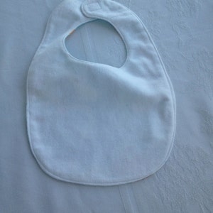 May include: A light blue baby bib with a white snap closure.