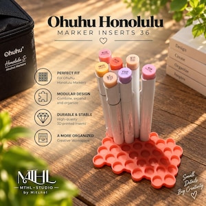 May include: A coral-coloured, honeycomb-patterned plastic marker organiser insert holding seven Ohuhu Honolulu alcohol markers. The organiser features a modular design with circular slots for individual markers, displayed alongside a black carrying case.
