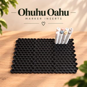 Può includere: Un vassoio organizzatore per pennarelli in plastica nera con una griglia di alloggiamenti circolari per pennarelli Ohuhu Oahu. Il testo Ohuhu Oahu MARKER INSERTS è visualizzato sopra il vassoio, che contiene alcuni pennarelli con tappi chiari.