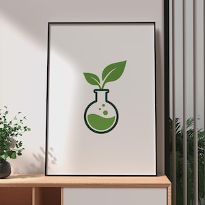 Può includere: Una stampa artistica da parete incorniciata che presenta un grafico verde scuro di un pallone da laboratorio a fondo tondo. All'interno del pallone c'è un liquido verde solido con bolle e due foglie verdi spuntano dall'apertura superiore.
