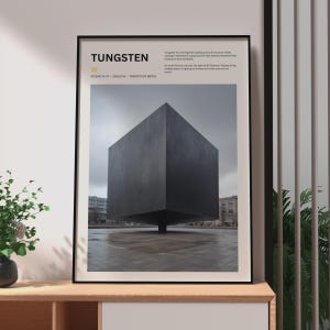 May include: A framed wall art print titled TUNGSTEN featuring a large, dark gray cube sculpture centered in an outdoor plaza. The text includes the element symbol W, atomic number 74, group 6, and a brief description of the metal's properties.