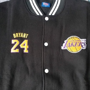 May include: Black varsity jacket with white and black striped collar and cuffs. Features the name "Bryant" and the number "24" in gold and purple. Includes a Los Angeles Lakers logo.