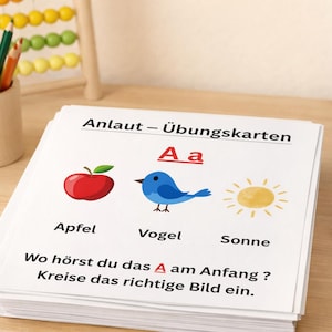 Könnte beinhalten: Ein Stapel Lernkarten mit den deutschen Wörtern "Apfel", "Vogel" und "Sonne" und entsprechenden Illustrationen von Apfel, Vogel und Sonne. Der Text "Anlaut - Übungskarten" steht oben. Ein Stifthalter, Bleistifte und ein Abakus befinden sich im Hintergrund.