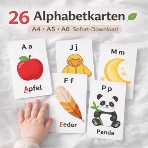 以下が含まれることがあります： カラフルなイラストが描かれたアルファベットカードのセット。赤いリンゴ、黄色のジャケット、三日月、羽、パンダなどの画像がカードに表示されています。「26 Alphabetkarten」の文字が上部にあります。