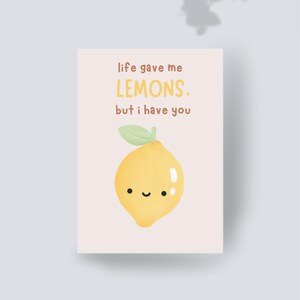 Pode incluir: Um cartão de felicitações retangular com fundo rosa claro apresentando uma ilustração de um limão amarelo com um rosto sorridente e uma folha verde. O texto diz: life gave me LEMONS. but i have you. O design está centrado no cartão.