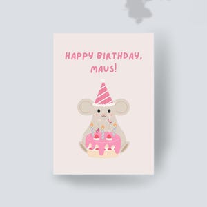 Puede incluir: Una tarjeta de felicitación rectangular con fondo rosa claro que muestra un ratón de dibujos animados con un gorro de fiesta a rayas rosas y blancas. El ratón está sentado detrás de un pastel de cumpleaños con glaseado rosa y tres velas. Texto HAPPY BIRTHDAY, MAUS!