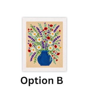 May include: A framed needlepoint artwork featuring a vibrant bouquet of flowers in a blue vase. The flowers include white daisies, red poppies, and purple lavender. The background is a beige color, and the frame is white. The text "Option B" is at the bottom.