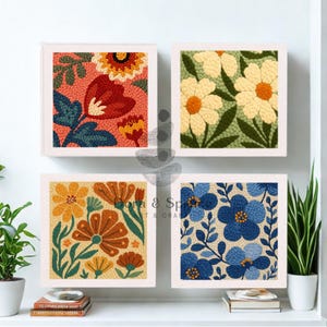 Peut inclure: Quatre œuvres d'art florales encadrées. Chaque carré présente un motif floral différent aux couleurs vives : rouge, orange, jaune et bleu. L'œuvre est exposée sur un mur blanc au-dessus d'une étagère avec des livres et des plantes.
