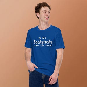 May include: A royal blue t-shirt with the text "IN MY Backstroke ERA" in white, with wave graphics. The shirt is made of a soft material and is suitable for casual wear.