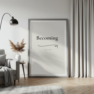 May include: A framed print featuring the word "Becoming" in black, minimalist lettering. Beneath the word is a curved line and the phrase "again and again". The print is displayed in a living room with a grey sofa and a floor lamp.
