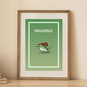 May include: A framed art print with a cartoon illustration of a green frog wearing a brown hat. The frog is set against a gradient green background with the word "PARASAUFROGUS" in white text.