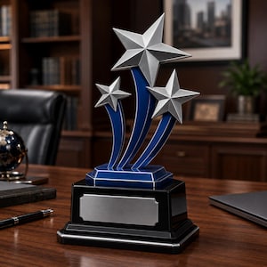 Op de afbeelding: Een trofee met drie zilverkleurige sterren op gebogen blauwe steunen. Het geheel staat op een getrapte zwarte voet met een rechthoekig zilverkleurig plaatje aan de voorzijde, bedoeld voor gravures of het toevoegen van tekst of prijzen.