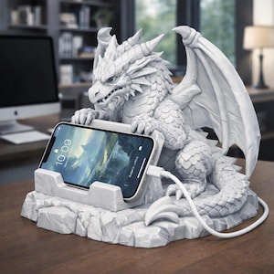 Puede incluir: Un soporte para teléfono con forma de dragón blanco con un teléfono inteligente. El dragón tiene escamas, alas y cuernos detallados. El teléfono muestra una imagen de paisaje y está conectado a un cable de carga blanco. El soporte se encuentra sobre una base texturizada.