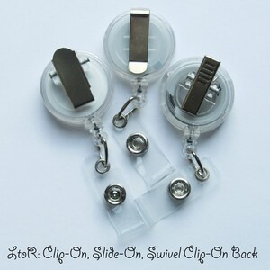 May include: Three clear plastic retractable badge holders with different clip styles. From left to right: a clip-on, a slide-on, and a swivel clip-on.