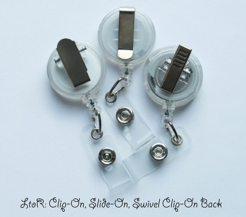 May include: Three clear plastic retractable badge holders with different clip styles. From left to right: a clip-on, a slide-on, and a swivel clip-on.
