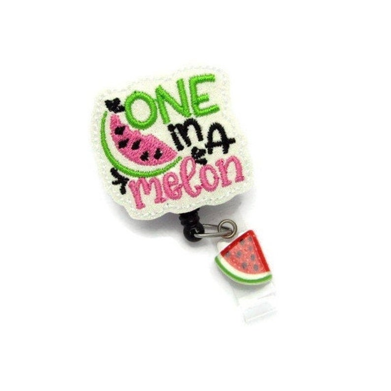 May include: White embroidered badge holder with a watermelon design and the text "One in a melon". The badge holder has a retractable cord and a small watermelon charm.