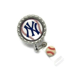 May include: A baseball-themed retractable badge reel. The reel features a silver bottle cap design with the New York Yankees logo in navy blue on a white background. A small baseball charm is attached.