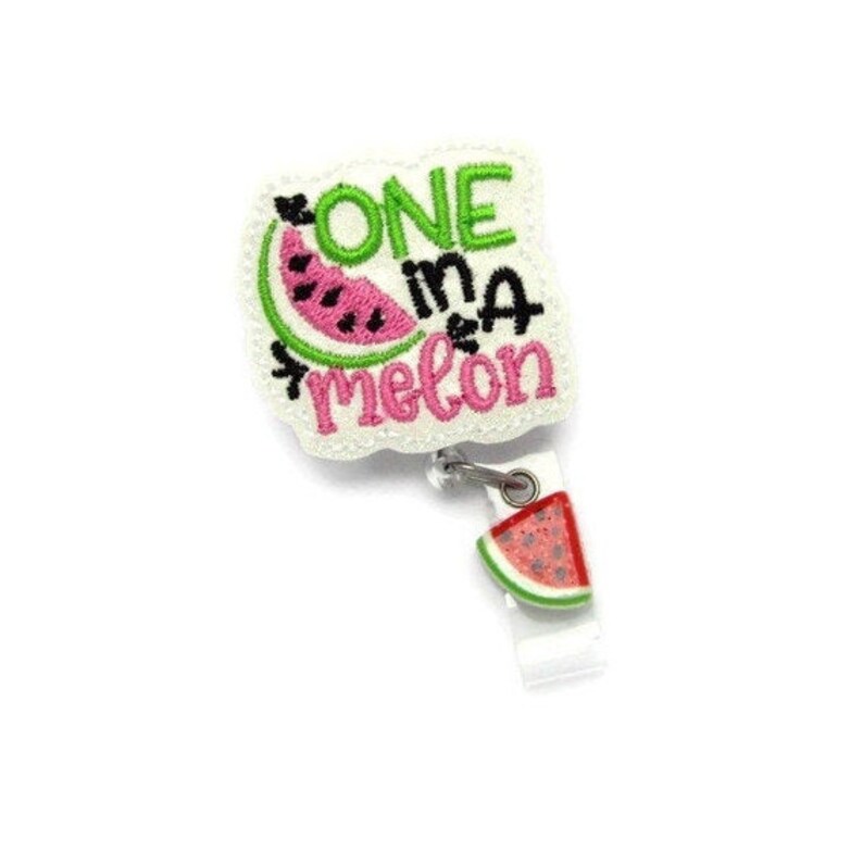 May include: White embroidered badge with the text "One in a melon" and a watermelon graphic. A small watermelon charm hangs from the badge.