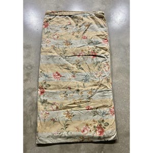 Può includere: Una trapunta in tessuto rettangolare caratterizzata da strisce orizzontali alternate in beige tenue e azzurro pallido. La superficie è decorata con un motivo floreale ripetuto composto da rose rosa, piccoli fiori gialli e fogliame verde.