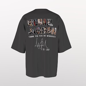Puede incluir: Camiseta gris oscuro con el nombre "MICHAEL JACKSON" compuesto por collages de fotos. Debajo, el texto "THANK YOU FOR THE MEMORIES" y una firma. La camiseta también muestra los años "1958 - 2009".