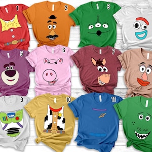 Puede incluir: Una colección de doce camisetas de manga corta y cuello redondo con diversos diseños inspirados en personajes. Las camisetas se muestran en una cuadrícula, cada una con colores únicos y estampados gráficos que representan rostros y atuendos.