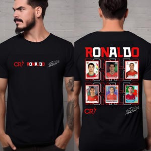 Puede incluir: Una camiseta negra de manga corta con un gráfico frontal con el texto CR7, RONALDO y una firma. La parte posterior muestra el texto RONALDO en rojo, seis tarjetas de retrato individuales de Cristiano Ronaldo, el logotipo CR7 y una firma blanca.