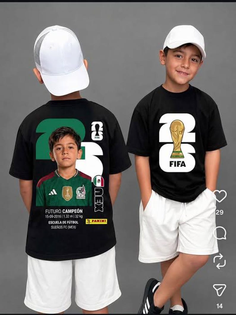 May include: A black t-shirt featuring a large white 26 graphic with a gold FIFA World Cup trophy on the front. The back displays a photo of a child in a green soccer jersey, the text FUTURO CAMPE&Oacute;N, 15-09-2016, 1.32 m, 32 kg, ESCUELA DE F&Uacute;TBOL, SUE&Ntilde;OS FC, and PANINI.