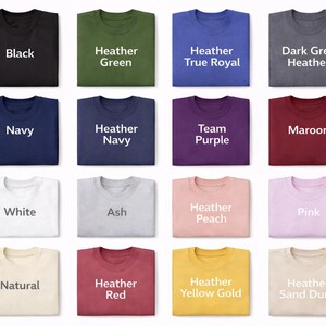 May include: A grid of sixteen folded t-shirts in various colors, each labeled with its color name in white or dark text. The colors include black, heather green, heather true royal, dark grey heather, navy, heather navy, team purple, maroon, white, ash, heather peach, pink, natural, heather red, heather yellow gold, and heather sand dune.