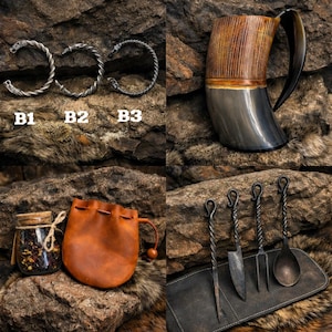 K&ouml;nnte beinhalten: Eine Sammlung von Gegenst&auml;nden, darunter drei gedrehte Metallarmb&auml;nder mit der Beschriftung B1, B2 und B3, ein gro&szlig;er Trinkbecher aus Horn, ein kleines Glas mit getrockneten Kr&auml;utern, ein brauner Lederbeutel und vier geschmiedete Metallbestecke.
