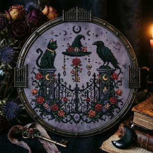 May include: A framed cross-stitch featuring a black cat and raven perched on pillars, flanking a witch's hat and gate. The design includes roses, keys, moons, and stars, all in a gothic, Halloween theme. The frame is dark metal.
