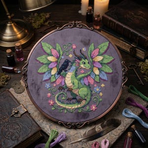 May include: A cross-stitch embroidery of a green dragon with colorful wings and a black bird perched on its back, set in a round, bronze-colored frame. The dragon is surrounded by flowers and foliage, with a dark purple background.