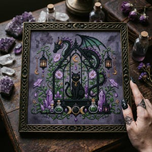 magical fantasy cross-stitch pattern featuring a black cat sitting inside a gothic greenhouse while a dark dragon with green wings curls protectively around the roof. The scene is decorated with lavender flowers, leafy vines, purple crystals, potion bottles, hanging lanterns, crescent moon charms, and celestial ornaments. The rich palette of black, green, lavender, gray, purple, and gold creates a mystical witchy garden mood, perfect for cat lovers, dragon fans, fantasy décor, and handmade walL