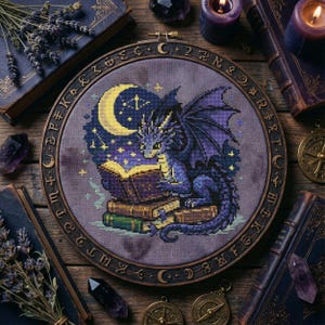 Puede incluir: Un bordado de punto de cruz con un dragón azul leyendo un libro bajo una luna creciente y estrellas. El diseño está en un aro de madera con símbolos celestiales, rodeado de libros antiguos, velas y cristales.