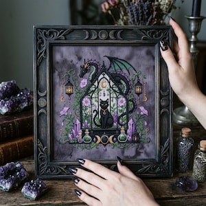 magical fantasy cross-stitch pattern featuring a black cat sitting inside a gothic greenhouse while a dark dragon with green wings curls protectively around the roof. The scene is decorated with lavender flowers, leafy vines, purple crystals, potion bottles, hanging lanterns, crescent moon charms, and celestial ornaments. The rich palette of black, green, lavender, gray, purple, and gold creates a mystical witchy garden mood, perfect for cat lovers, dragon fans, fantasy décor, and handmade walL