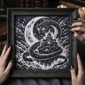 May include: Framed black and white cross-stitch artwork. It depicts a serpent coiled around a pagoda, set against a crescent moon and starry sky. The frame is dark wood.