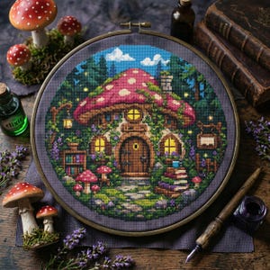 Peut inclure: Une broderie au point de croix représentant une maison champignon fantaisiste avec un chapeau rouge et blanc à pois. La scène comprend une porte en bois, des fenêtres lumineuses et une végétation luxuriante, le tout encadré dans un cercle.