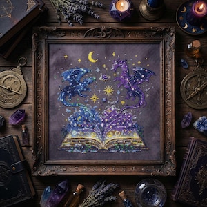 May include: A framed cross-stitch featuring two dragons with starry patterns, facing each other above an open book. The artwork is in shades of blue and purple, with a crescent moon and stars. The frame is dark brown, and the background is a dark purple.