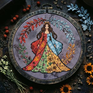 Puede incluir: Bordado de punto de cruz de una mujer con un vestido dividido, enmarcado en un aro de madera. El vestido está dividido en secciones rojas, verdes y amarillas, con motivos florales y de girasoles. La mujer está coronada, rodeada de follaje otoñal e invernal.