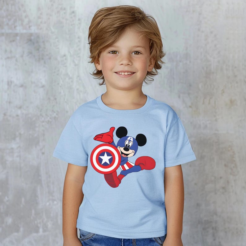 Peut inclure: Un t-shirt bleu clair avec Mickey Mouse en Captain America. Le personnage tient un bouclier avec une &eacute;toile blanche et des d&eacute;tails rouges et bleus. Le t-shirt a des manches courtes et un col rond.